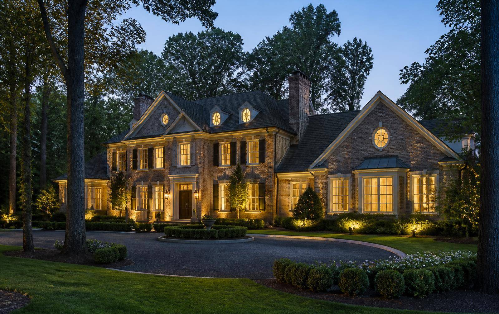 Brick and stone luxury estate home lit at twilight in a Charlotte country club neighborhood