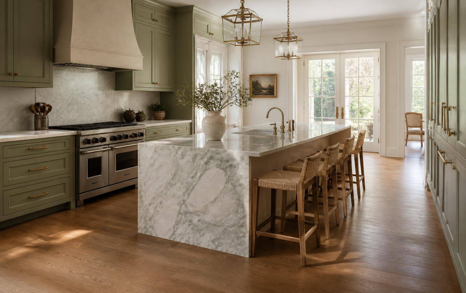 Renovated kitchen with honed marble island, green inset cabinetry and brass lanterns
